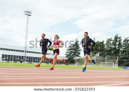 Group of young  athletics people running on the track field