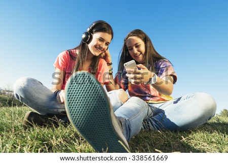 happy beautiful teen friends in summer park listening music.