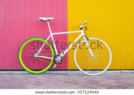 City bicycle fixed gear on yellow and red wall. Cycling or commuting in city urban environment, ecological transportation concept.