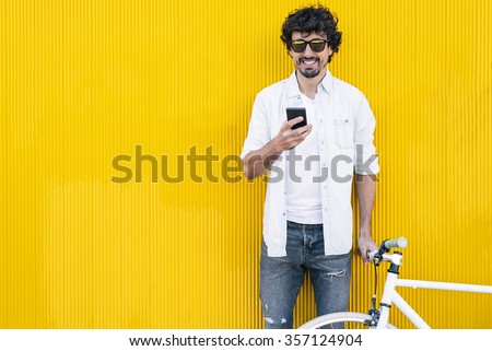 Outdoor portrait of handsome young man with mobile phone and fixed gear bicycle in the street.