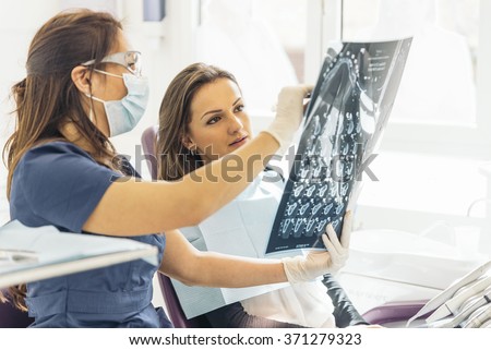 Doctor talking with her patient and teaching a radiograph. Dentist concept.