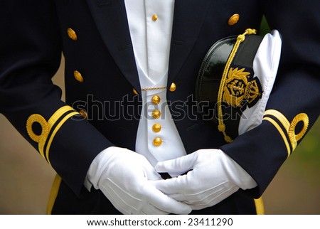 Close-up of a navy officer in uniform with his cap under his left arm.