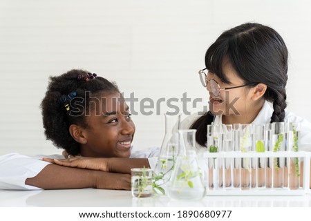 Asian girl and African American girl scientists learning and doing analysis for germs with glassware in the laboratory. Educational. Early development of children. Research and development concept