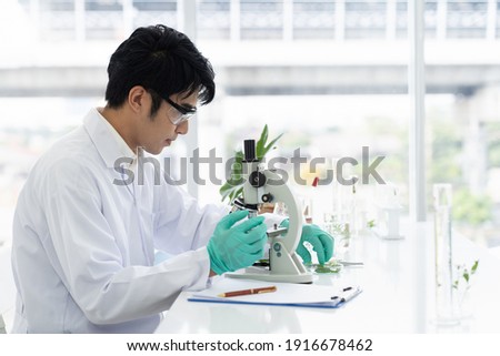 Scientists tests of plants in laboratory. Asian male scientists doing analysis for germs and bacteria with microscope in the laboratory. Scientific experiment. researcher and discovery concept