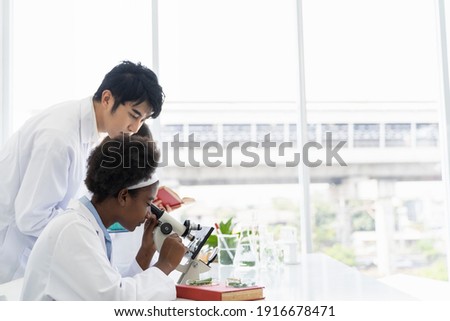 Asian teacher and diverse student doing tests of plants in classroom. Group of diversity scientists learning science and doing analysis for germs and bacteria with microscope in the laboratory