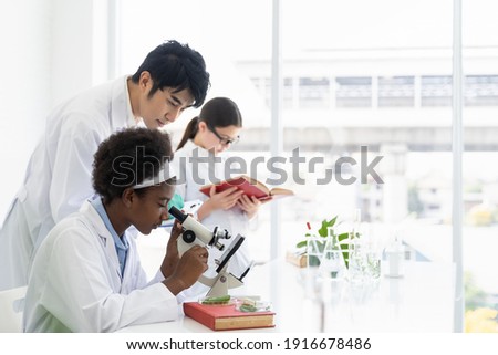 Asian teacher and diverse student doing tests of plants in classroom. Group of diversity scientists learning science and doing analysis for germs and bacteria with microscope in the laboratory