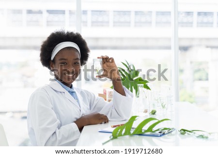 African American girl scientists holding glassware for tests of plants in the classroom. Girl learning science and doing analysis in the laboratory. Science experiment. Early development of children