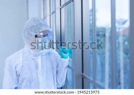 Asian man scientist is wearing Personal Protective Equipment (PPE) looked at the window while in laboratory. Homesick ,Disease quarantine Impact Coronavirus
