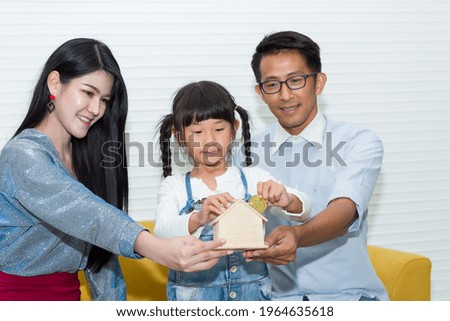 Young Asian father, mother and their cute little daughter saving money with bitcoin at home concept