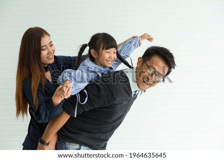Happy Asian family having fun with home. Asian father playing and carrying little daughter on back at home with happy and smile