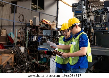Factory male worker discussing and looking clipboard document for maintenance machine lathe metal in the industry factory. Engineer worker using manual document for lathe machine in the factory