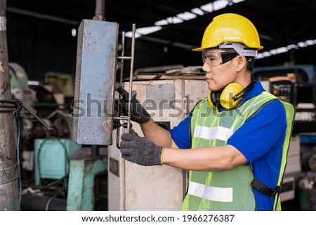 Asian engineer male worker maintaining machine lathe metal at the industry factory. Asian factory worker check or maintenance CNC machine in industry factory