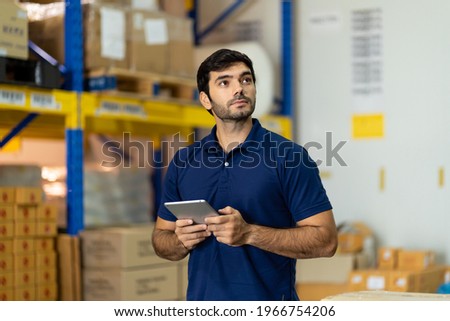 Portrait of warehouse male worker using digital tablet in factory warehouse. Inspection quality control