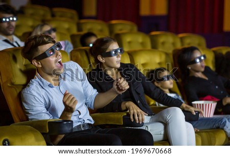 Group of enjoying people while watching the movie at the cinema theatre with 3D glasses