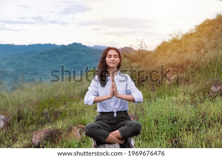 Young woman doing meditate yoga asana with eyes closed in the mountain on forest background. Female practicing doing yoga outdoor