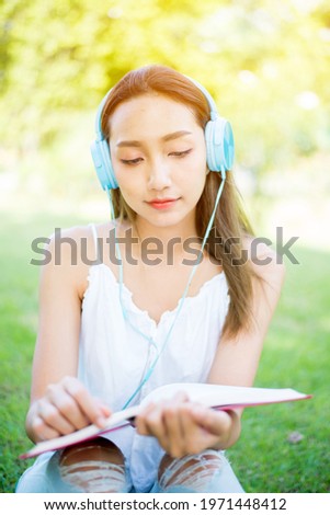 Asian student reading book alone in the park on spring day. Relax and recreation. Outdoor activity and lifestyle on holiday.