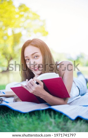 Asian woman reading book alone in the park on spring day. Relax and recreation. Outdoor activity and lifestyle on holiday.