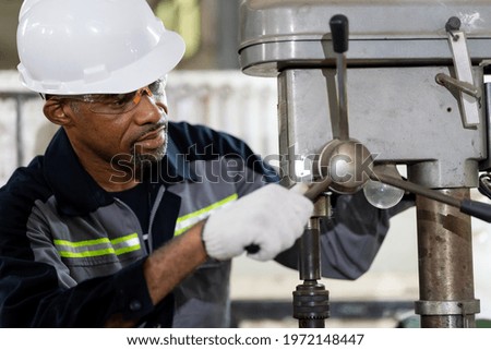 African American male engineer worker maintenance lathe machine in the factory. Black male worker working with machine with safety uniform, goggles and helmet