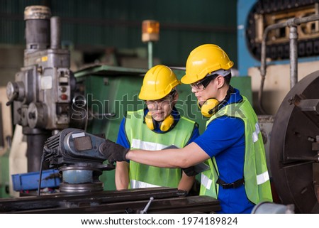 Two Asian engineer male worker maintaining machine lathe metal at the industry factory. Group of Asian factory worker working or maintenance machine in industry factory