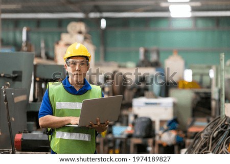 Portrait of Asian male factory worker working with laptop computer in the industry factory. Male engineer working with laptop computer in the factory