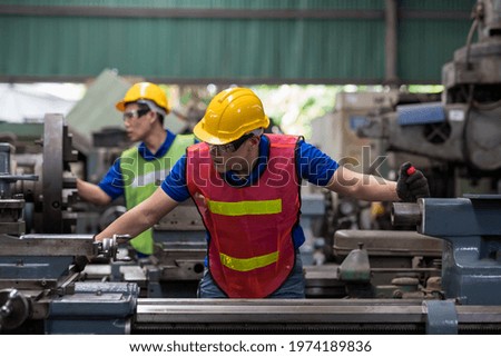 Two Asian engineer male worker maintaining machine lathe metal at the industry factory. Group of Asian factory worker working or maintenance machine in industry factory