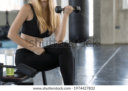 Woman lifting dumbbell weight while sitting at the gym, sports training with weight, Exercise fitness and healthy lifestyle