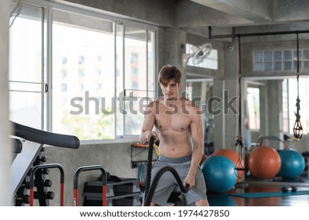 Man doing with battle rope in the gym. gym, sport, rope, workout and exercises concept