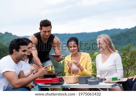 Group of diverse young tourist friends camping, cooking on mountain. Group of young traveler women cooking together on camping holiday