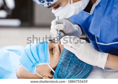 Latin Cosmetologist preparing to mexican woman for eyebrow permanent makeup procedure in Mexico, Microblading closeup