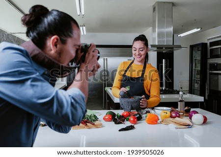 latin woman Food Blogger shooting food on table while a photographer man is taking pictures with camera of mexican food at kitchen in mexico city