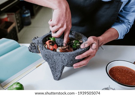mexican hands cooking a Mexican sauce whit chili and spices in a molcajete in kitchen in Mexico city