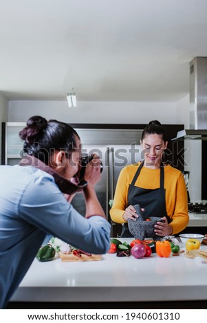latin couple cooking mexican sauce and food taking photo in the kitchen in Mexico city