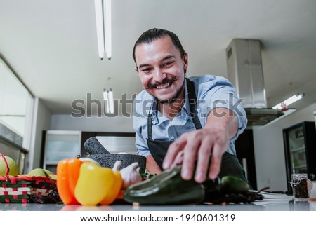hispanic man cooking at home preparing salad or mexican sauce in kitchen at home in Mexico city