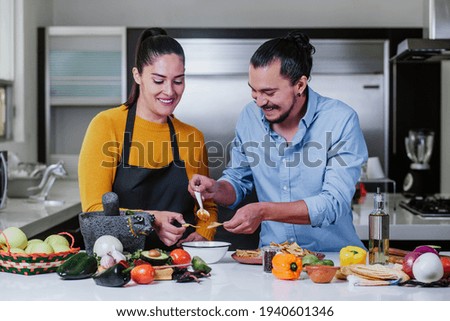 latin couple cooking mexican sauce together in their kitchen at home in Mexico city