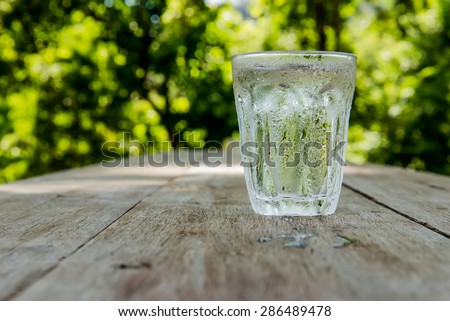 Glass of cold water shooting range Place the right side on a wooden table Focus on water drops on glass.