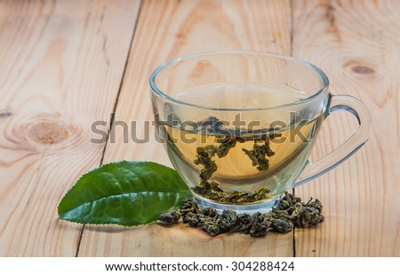 Tea, tea leaves, fresh and dried tea light wood lay on the floor, focus on the tea leaves and glass.