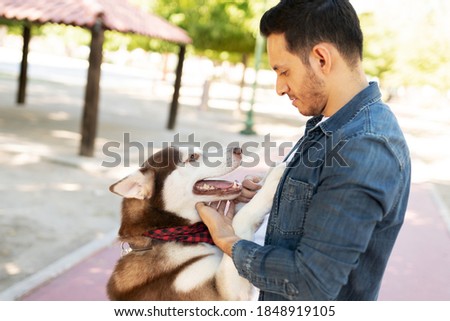 Attractive adult in his 30s looking at his happy husky dog face to face