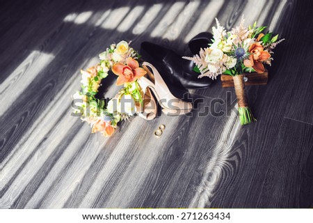 beautiful bridal bouquet in shades of green with a brooch in the form of clover \
on a background of green shoes and wedding rings of gold