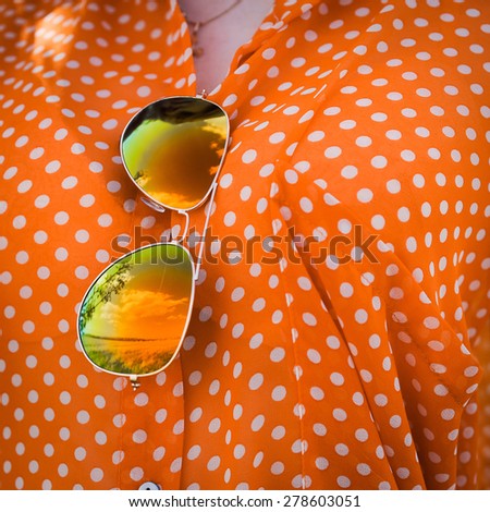 close-up portrait outdoors  girl in an orange hipster blonde bright cheerful polka dot blouse and in SLR sunglasses