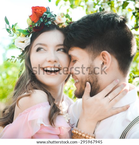portrait of a girl and couples looking for a wedding dress, a pink dress flying with a wreath of flowers on her head on a background tsvetuschago garden and the blue sky, and they hug and pose
