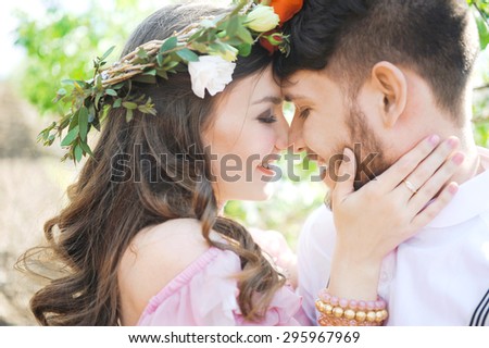 portrait of a girl and couples looking for a wedding dress, a pink dress flying with a wreath of flowers on her head on a background tsvetuschago garden and the blue sky, and they hug and pose