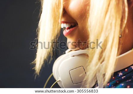 close-up portrait of a girl on a yellow background in studio beautiful young bright sexy hair in a ponytail, wearing headphones listening to music and singing and posing  \
with red lips and manicure