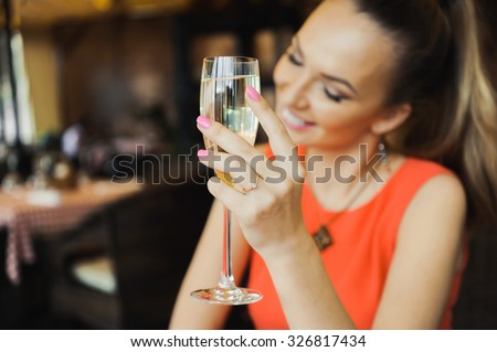 close-up portrait of a beautiful young elegant sexy blonde woman in the cafe with a glass of champagne,White wine  smiling  and drink posing, with a ring on her finger, she is engaged