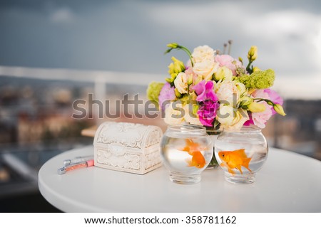 wedding ceremony on the roof against the backdrop of a stormy sky and white flowers on the table is worth two aquarium with goldfish for the bride and groom