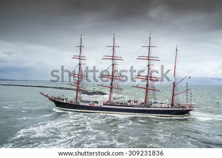 IJMUIDEN, NETHERLANDS - AUGUST 18 2015: Tall ship passing lighthouse in the rain storm