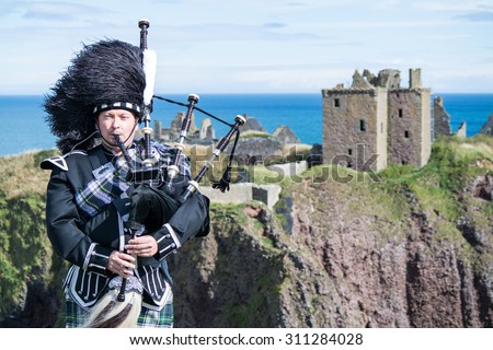 Traditional scottish bagpiper in full dress code at Dunnottar Castle in Stonehaven