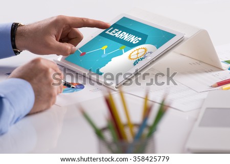 Businessman working on tablet with LEARNING on a screen