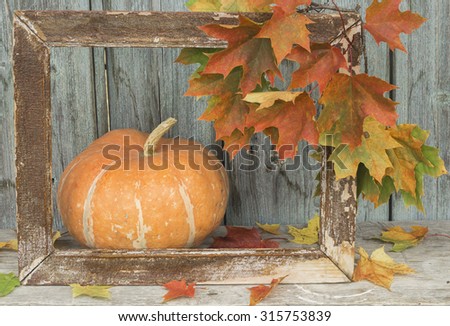 Maple leaves hanging in an old frame for a picture.Pumpkin lying on the garden bench with maple leaves.