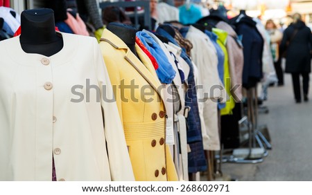 Row of mannequins with different coloured women\'s clothes on market. Some outwear examples in a line before shop. Clothes sale concept.