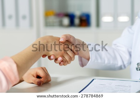 Female doctor shaking hands with patient. Partnership, trust and medical ethics concept. Handshake with satisfied client. Thankful handclasp for excellent treatment.
